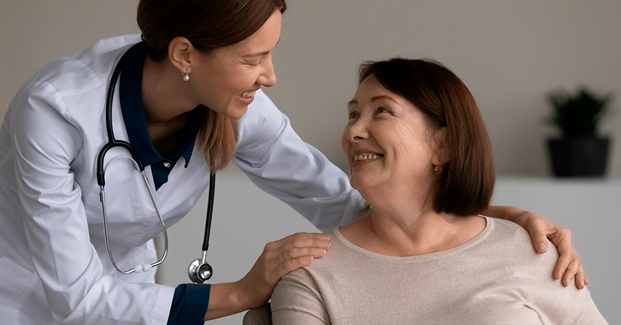 Doctora sonriendo y hablando con una paciente mayor